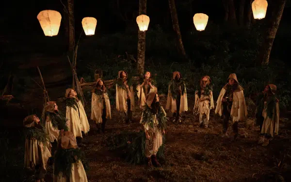 A haunting scene from the TV show Yellowjackets, featuring characters gathered in a forest at night, illuminated by glowing lanterns overhead. A striking 4K Ultra HD wallpaper.