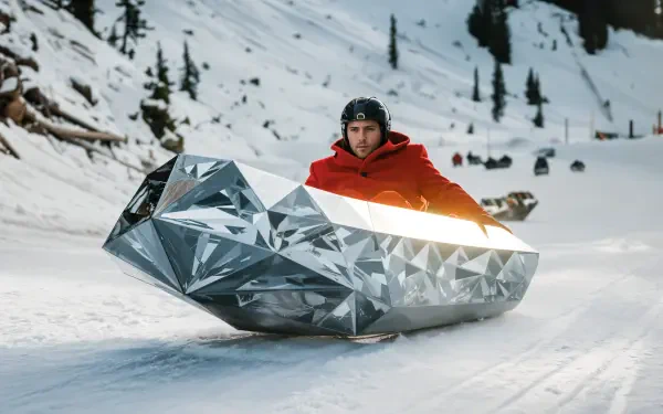 A person in a red jacket rides a sleek, diamond-shaped sled down a snowy slope, capturing the thrill of sledding. This vibrant scene makes a striking 4K Ultra HD desktop wallpaper.