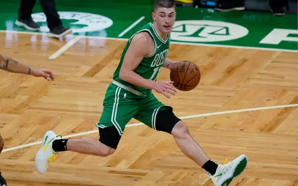 Payton Pritchard of the Boston Celtics dribbles the basketball during a game, showcasing his athleticism on the hardwood floor in this vibrant 4K Ultra HD wallpaper.