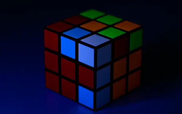 A close-up view of a Rubik's Cube illuminated against a dark background, showcasing vibrant colors and intricate patterns, perfect as a 4K Ultra HD PC desktop wallpaper.