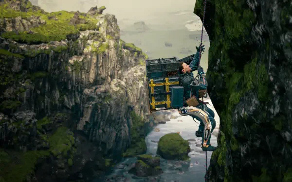 A character from Death Stranding 2: On The Beach climbs a rocky cliff, transporting a large cargo, with a scenic landscape of cliffs and water in the background. HD PC desktop wallpaper.