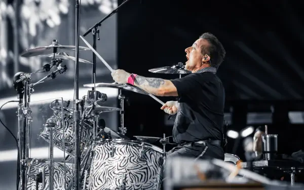 Tré Cool of Green Day passionately plays the drums during a live performance, captured in vibrant detail as part of a 4K Ultra HD desktop wallpaper.