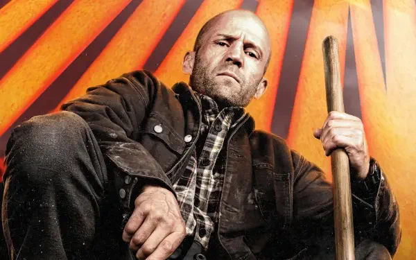 Jason Statham portrays a determined character in A Working Man, set against a striking backdrop with bold orange rays, captured in this vivid 4K Ultra HD wallpaper.