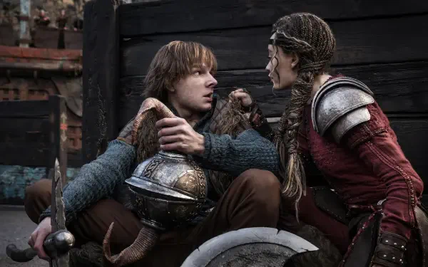 Hiccup and a warrior engage in a tense moment, surrounded by a rugged backdrop, in this 4K Ultra HD wallpaper from the upcoming movie How to Train Your Dragon (2025).