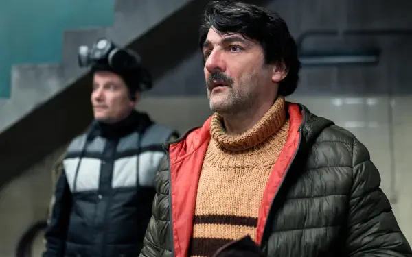 Scene from the TV show The Eternaut, featured as a 4K Ultra HD PC desktop wallpaper, showing two men in winter clothing indoors.