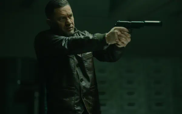 Tom Hardy in an intense scene from the TV show MobLand, captured in 8K Ultra HD, featuring him aiming a handgun in a dark, suspenseful setting.