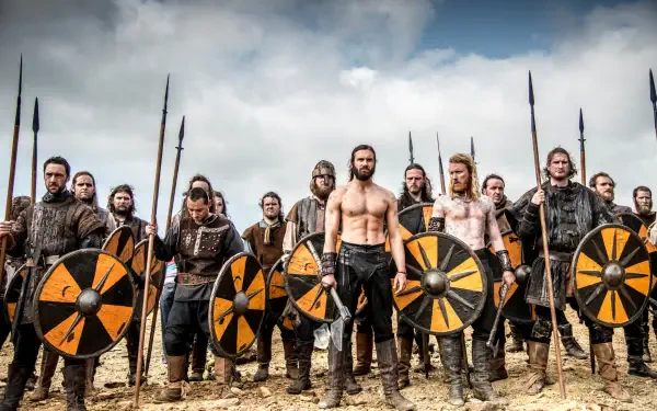 HD PC desktop wallpaper featuring a fierce group of warriors from Vikings (2013) standing ready with shields and spears under a cloudy sky.