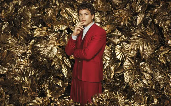 8K Ultra HD PC desktop wallpaper: a figure in a red suit poses amid metallic gold foliage — promotional image for The Hunger Games: The Ballad of Songbirds & Snakes.