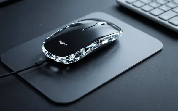 Logitech wired black mouse with crystal-trim sits on a mousepad beside a keyboard - 4K Ultra HD PC desktop wallpaper/background.