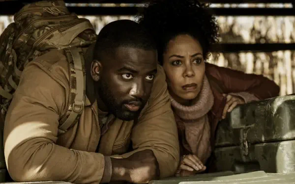 HD PC desktop wallpaper from TV show Invasion (2021): two tense characters crouch behind rubble, peering out from cover with military gear and wary expressions.