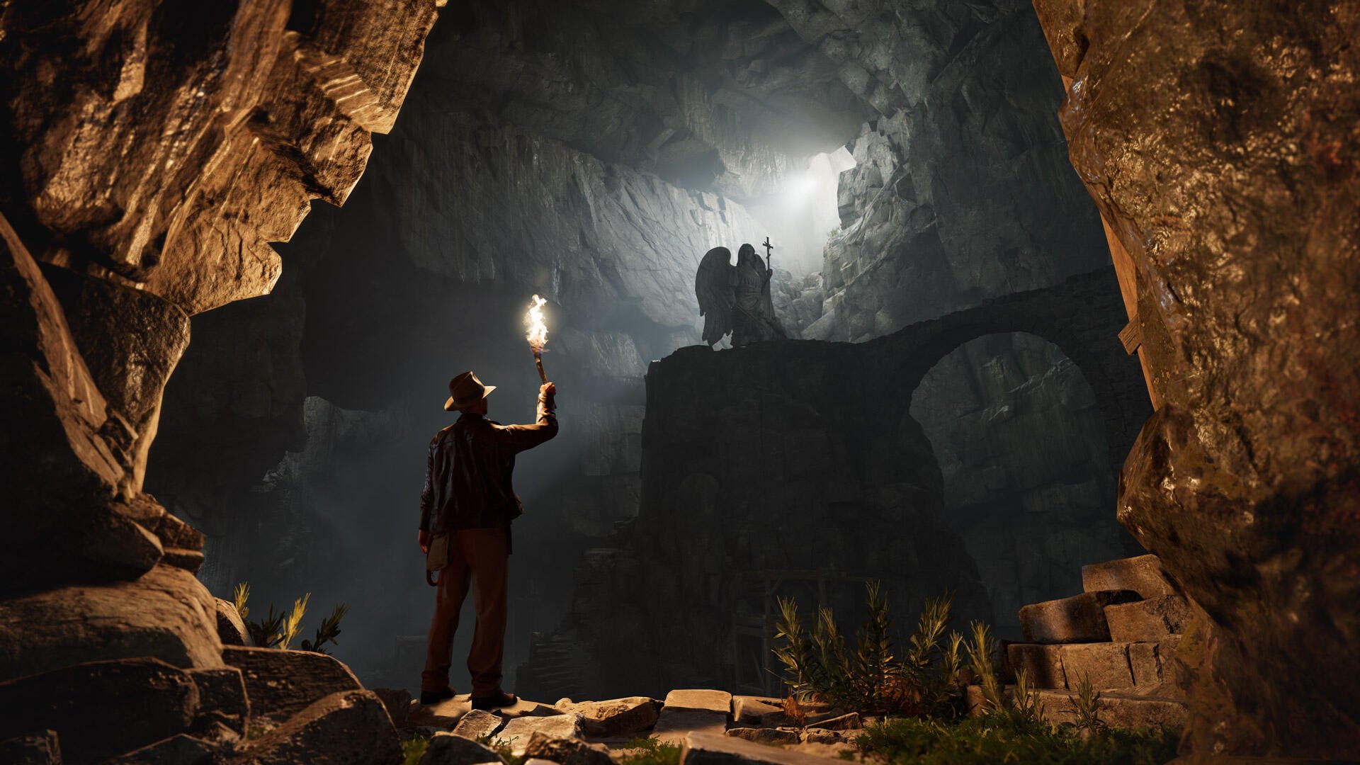 HD PC desktop wallpaper from the video game Indiana Jones and the Great Circle: explorer with torch in a vast, shadowy cavern, facing a silhouetted figure standing on a rocky ledge.