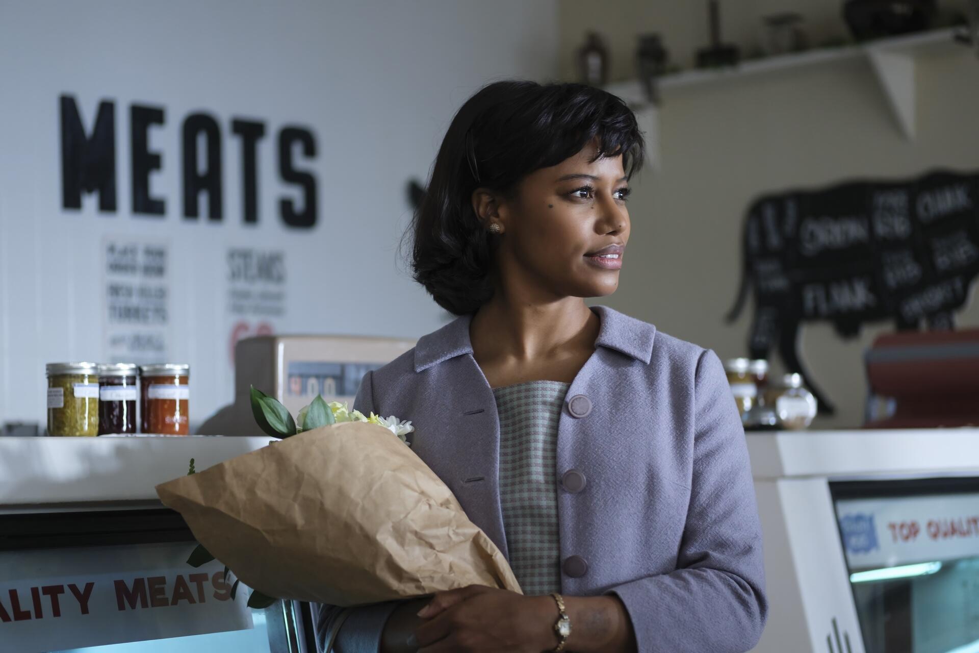 HD PC desktop wallpaper: still from TV show It: Welcome to Derry — woman holding a grocery bag in a butcher shop, looking off to the side.