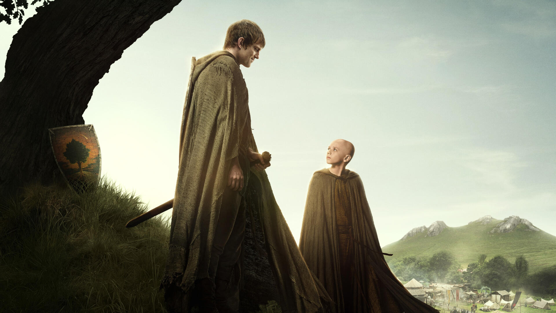 A Knight of the Seven Kingdoms 2K Quad HD PC desktop wallpaper: cloaked knight and young squire on a hill gazing over a misty valley.