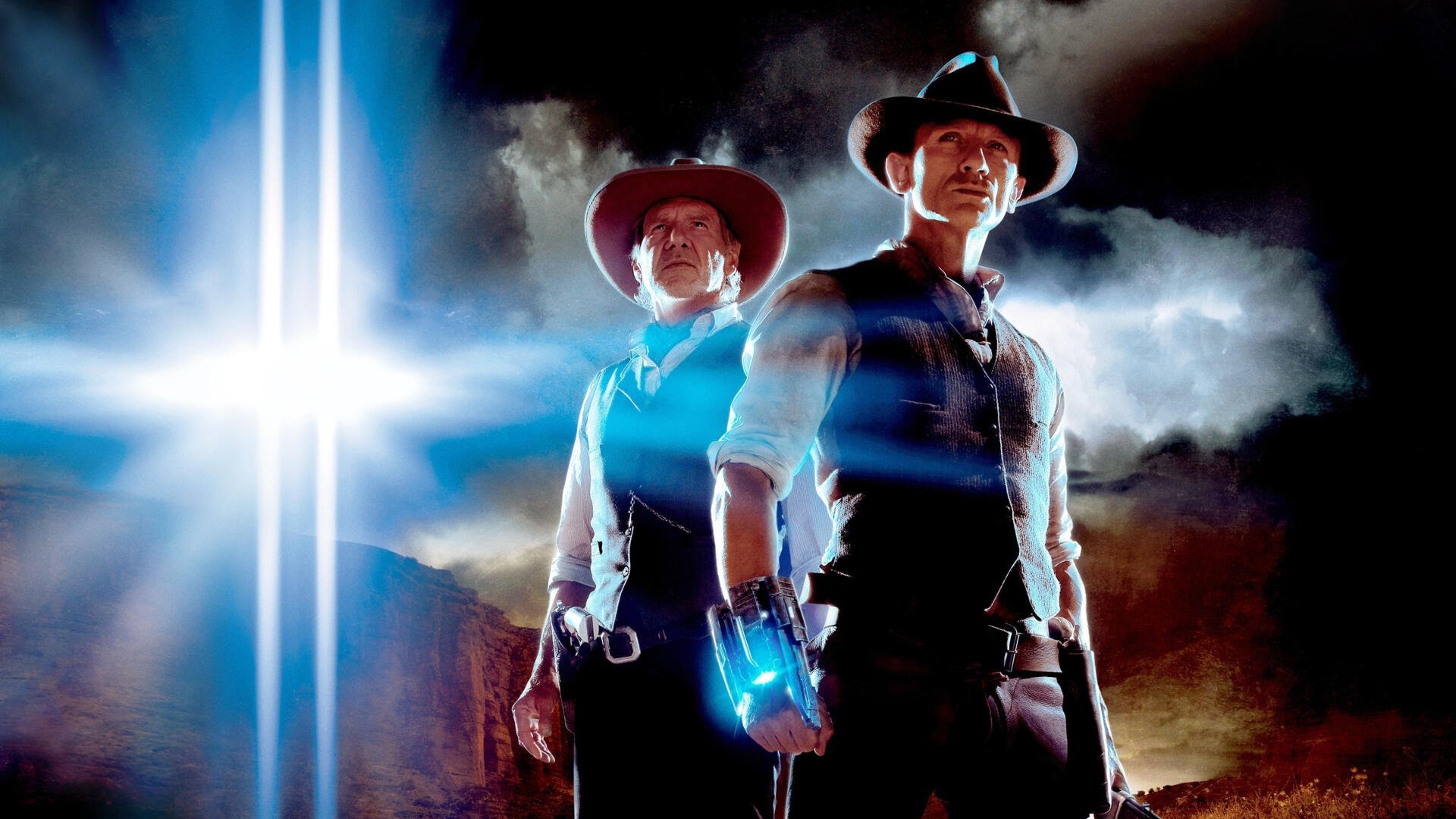 Cowboys & Aliens 4K Ultra HD PC desktop wallpaper: two armed cowboys back-to-back in a stormy desert, one with a glowing alien wrist device and bright beams of light piercing the sky.
