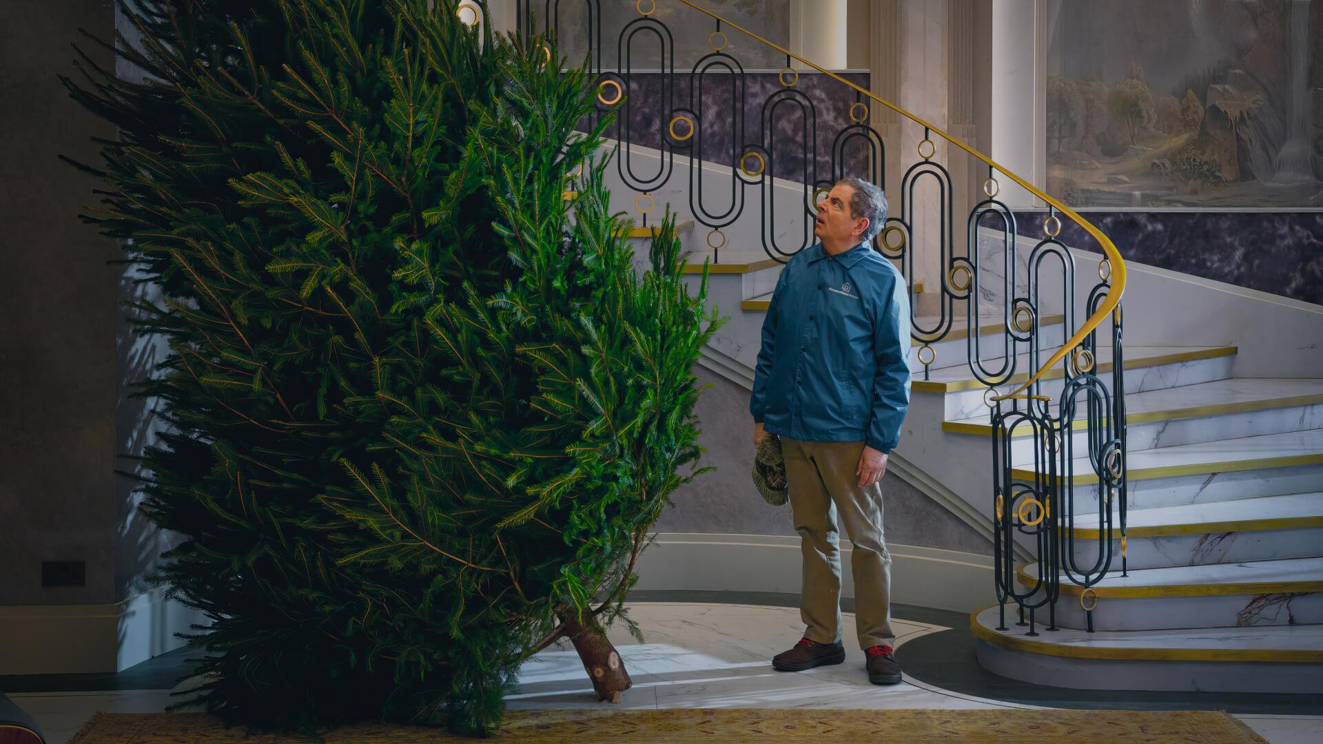 4K Ultra HD PC wallpaper from TV show Man vs Baby: a man in a blue jacket stares at an enormous Christmas tree beside an ornate curved staircase.