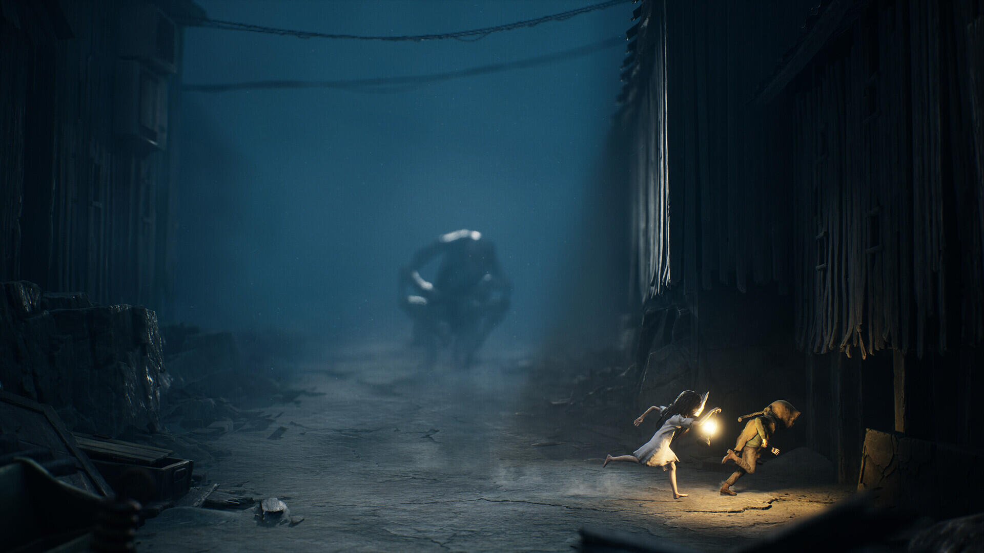 Horror game Reanimal HD PC desktop wallpaper: foggy alley with a hulking, shell-like monster looming as a small lantern-bearing figure huddles near scattered debris.