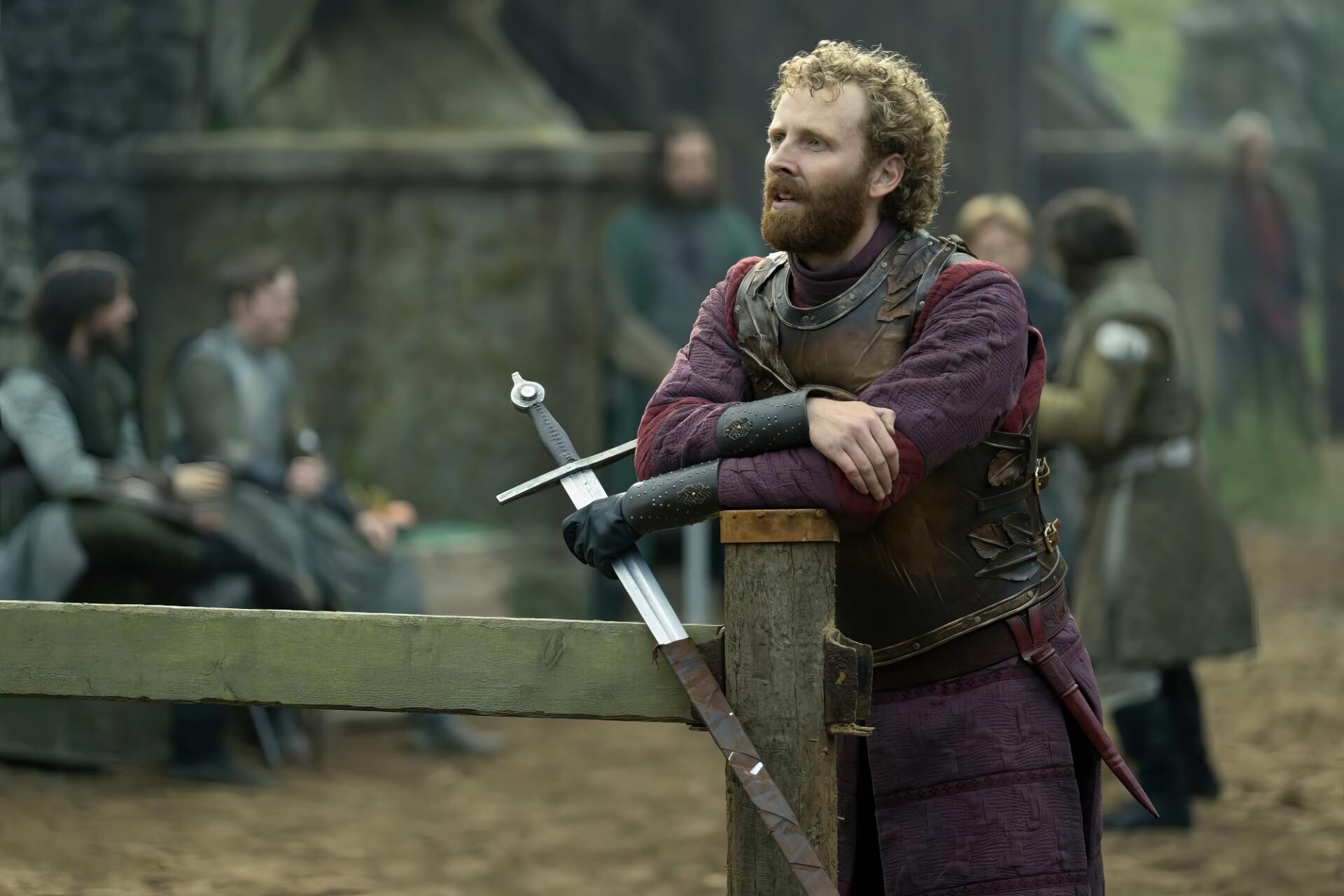 HD PC desktop wallpaper of a medieval knight in armor from the fantasy drama A Knight of the Seven Kingdoms, leaning on a fence with a sword.