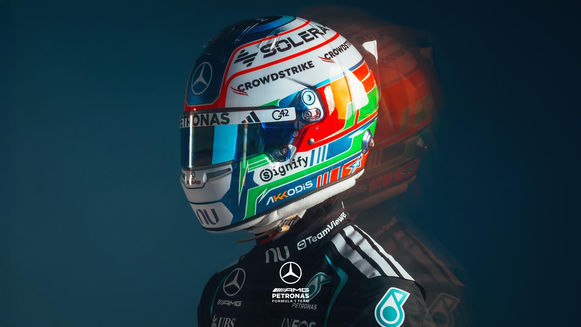 2K Quad HD PC desktop wallpaper: Mercedes AMG F1 driver wearing a colorful F1 helmet and team racing suit against a dark backdrop.