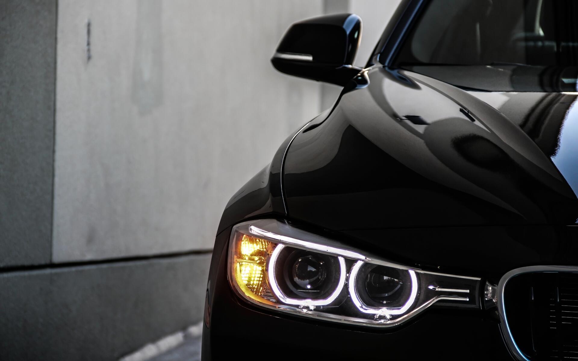 Close-up of a black BMW 328i front with illuminated BMW Eyes headlights, presented as a 2K Quad HD PC desktop wallpaper background.
