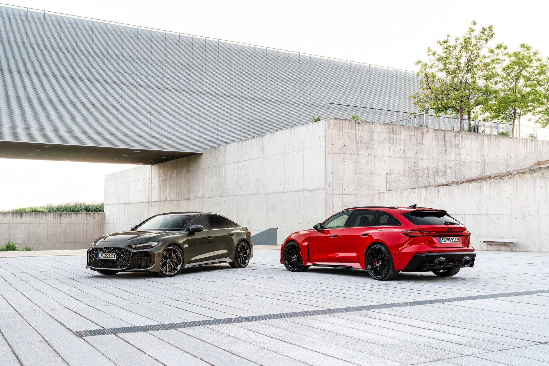 2K Quad HD PC desktop wallpaper: two Audi RS5 coupes—red and black—parked in a minimalist concrete urban setting.