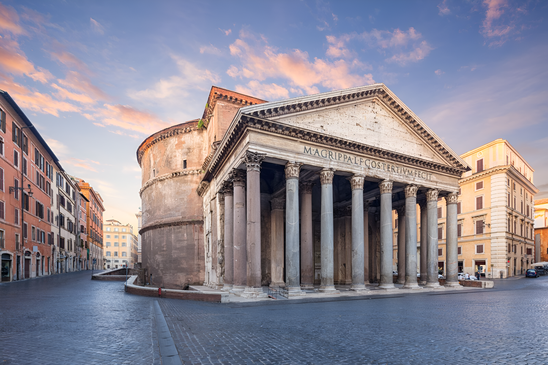 2K Quad HD PC desktop wallpaper and background of the Pantheon in Rome, Italy — classical Corinthian portico and rotunda bathed in warm sunset light, surrounded by city buildings.