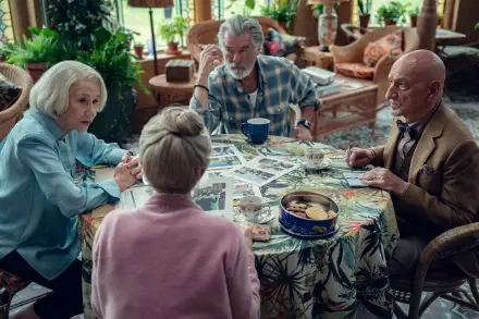 4K Ultra HD PC desktop wallpaper: scene from the movie The Thursday Murder Club — four older friends gathered around a floral table strewn with photos and clues in a cozy lounge.