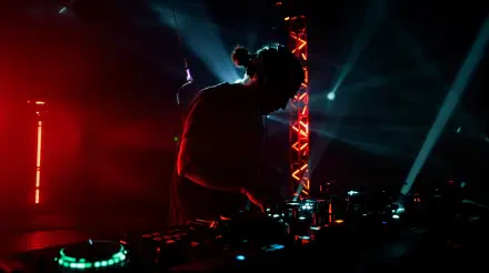 EDM 4K Ultra HD PC desktop wallpaper/background: silhouetted DJ at a neon-lit console, red and blue beams slicing smoke, illuminated truss and glowing mixer controls.