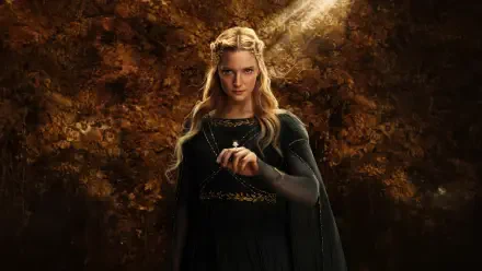 Galadriel from The Lord of the Rings: The Rings of Power, bathed in warm golden forest light and holding a small ring — 4K Ultra HD PC desktop wallpaper.