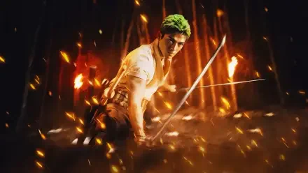 One Piece (Live Action) 2K Quad HD PC desktop wallpaper: green‑haired swordsman crouches with drawn blades amid flying sparks and roaring flames.