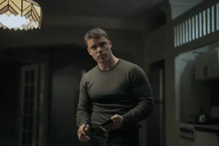 Thriller 2K Quad HD PC wallpaper: brooding man in a dim, shadowed kitchen holding a notebook, tense moody lighting evoking The Night Agent.