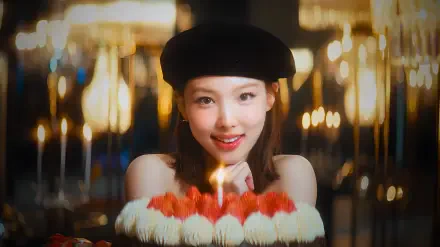 Smiling woman in a beret, K-pop idol–style model presenting a lit birthday cake with candles against warm bokeh lights — 4K Ultra HD PC desktop wallpaper background.