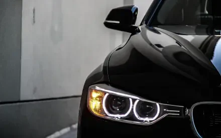 Close-up of a black BMW 328i front with illuminated BMW Eyes headlights, presented as a 2K Quad HD PC desktop wallpaper background.