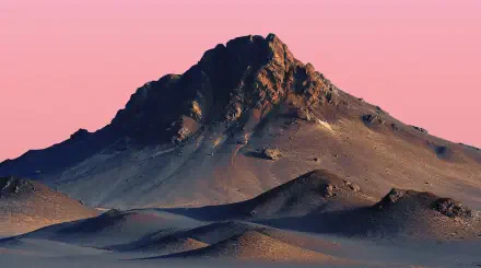 2K Quad HD PC desktop wallpaper: solitary desert mountain peak rising from rippled dunes beneath a soft pink sky.