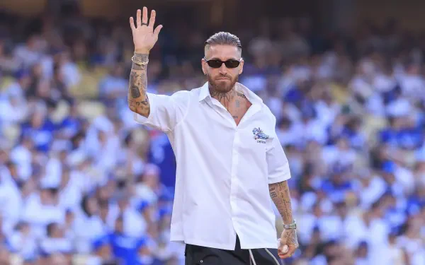 HD PC desktop wallpaper of a bearded, tattooed footballer in sunglasses waving to a cheering crowd in a packed stadium.