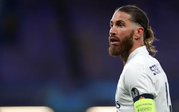 4K Ultra HD PC desktop wallpaper: bearded soccer captain in white kit with a yellow armband, glancing sideways beneath stadium lights.