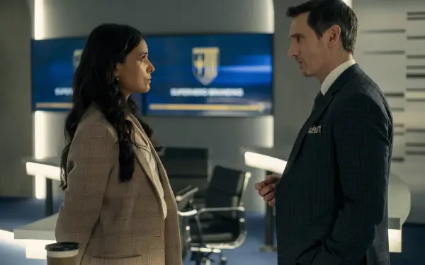 TV show Gen V — HD PC desktop wallpaper/background: two characters face each other in a sleek corporate office, a tense conversation by chairs and a wall screen showing an emblem.