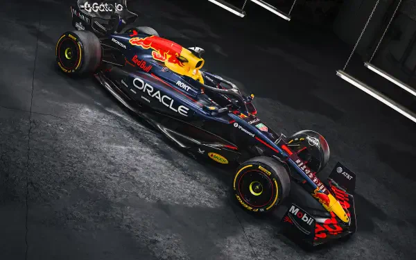 Red Bull RB21 F1 race car angled on a dark textured floor, vivid livery and Oracle branding — 2K Quad HD PC desktop wallpaper background.