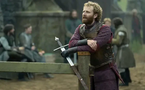 HD PC desktop wallpaper of a medieval knight in armor from the fantasy drama A Knight of the Seven Kingdoms, leaning on a fence with a sword.