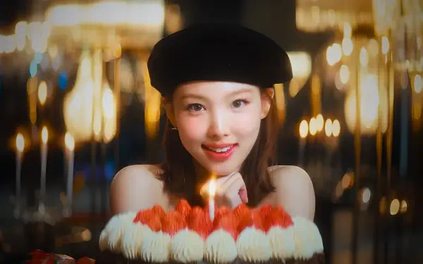 Smiling woman in a beret, K-pop idol–style model presenting a lit birthday cake with candles against warm bokeh lights — 4K Ultra HD PC desktop wallpaper background.