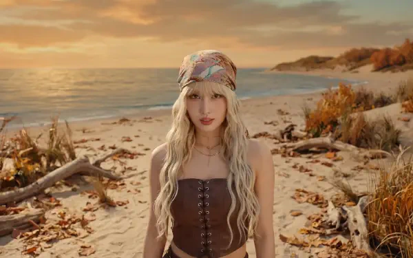 Blonde woman in a boho headscarf and brown corset standing on a sunlit sandy beach at sunset — 5K Ultra HD desktop wallpaper.