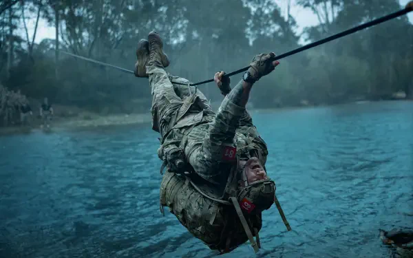 Movie still, War Machine (2026): soldier in military training crosses a rope over a lake, dramatic 5K Ultra HD PC desktop wallpaper background.