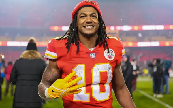 Smiling Kansas City Chiefs football player with dreadlocks wearing a red #10 jersey on the field — HD desktop wallpaper background.