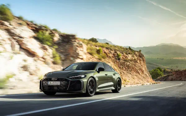 Audi RS5 driving on a sunlit winding mountain road with rocky cliffs and distant valley; 2K Quad HD PC desktop wallpaper/background.