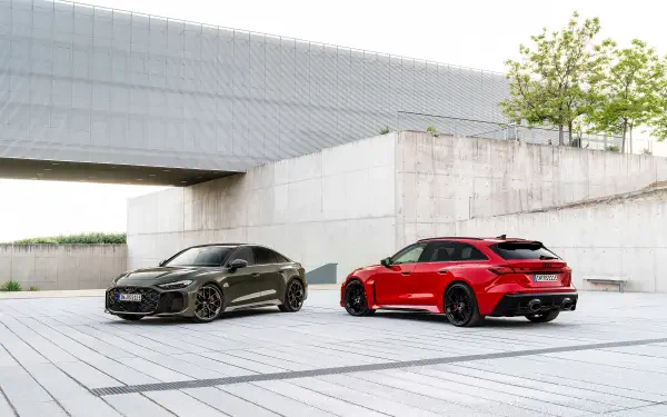 2K Quad HD PC desktop wallpaper: two Audi RS5 coupes—red and black—parked in a minimalist concrete urban setting.
