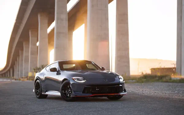 4K Ultra HD PC desktop wallpaper of a gray Nissan Z Nismo parked beneath an overpass at sunset, low-angle view with warm backlighting.