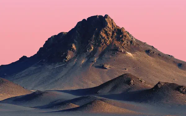 2K Quad HD PC desktop wallpaper: solitary desert mountain peak rising from rippled dunes beneath a soft pink sky.