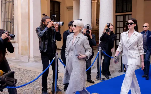 5K Ultra HD PC desktop wallpaper for The Devil Wears Prada 2: two stylish women in sunglasses walk a blue carpet while photographers snap photos.