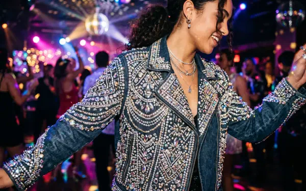 Smiling dancer in a bedazzled jacket twirls beneath disco lights amid a colorful club crowd — vibrant 5K Ultra HD PC Desktop Wallpaper and Background.
