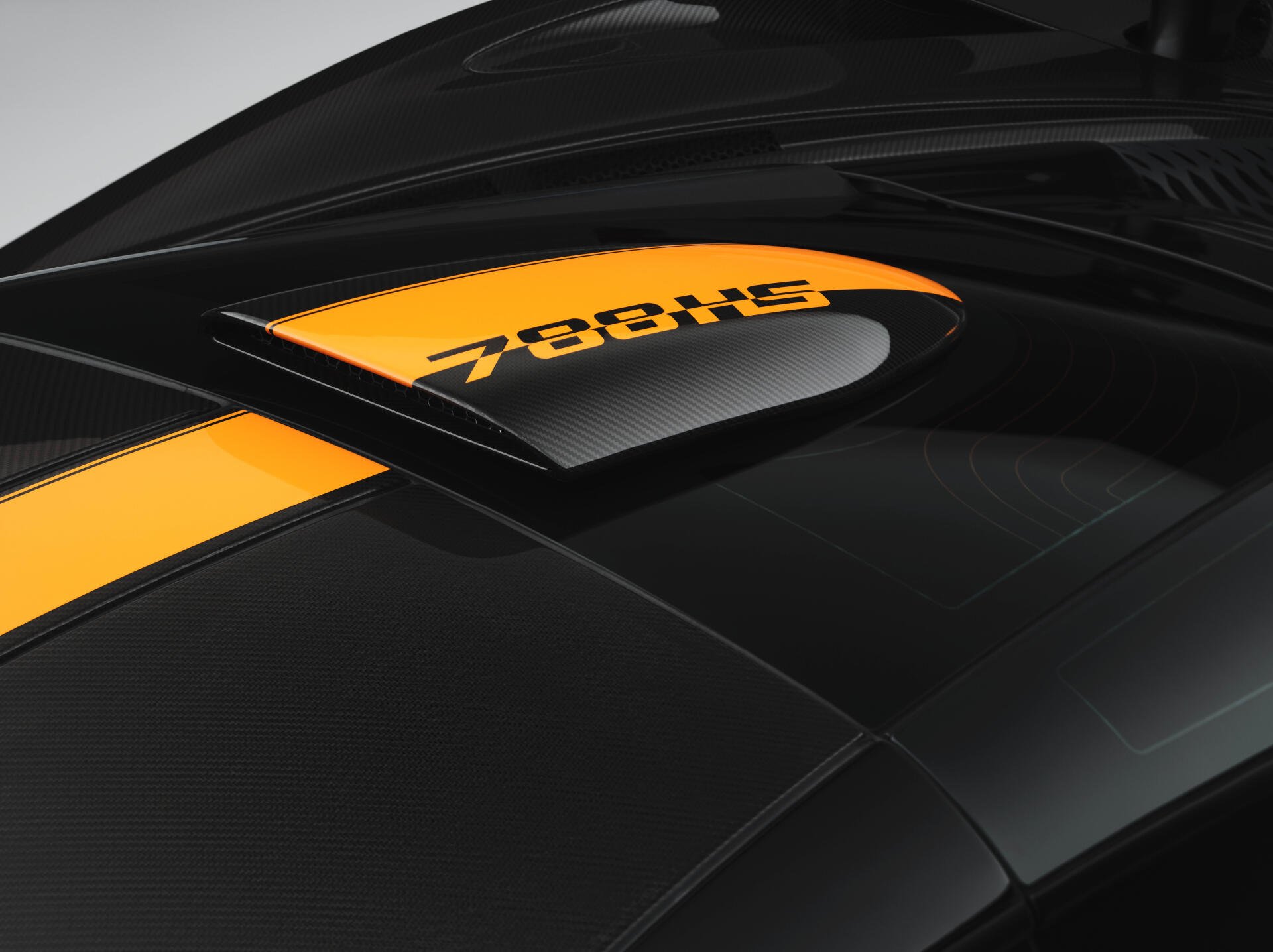 Close-up of a black carbon-fiber McLaren 788HS rear deck with yellow stripe and 788HS badge — 8K Ultra HD PC desktop wallpaper and background, vehicle detail.