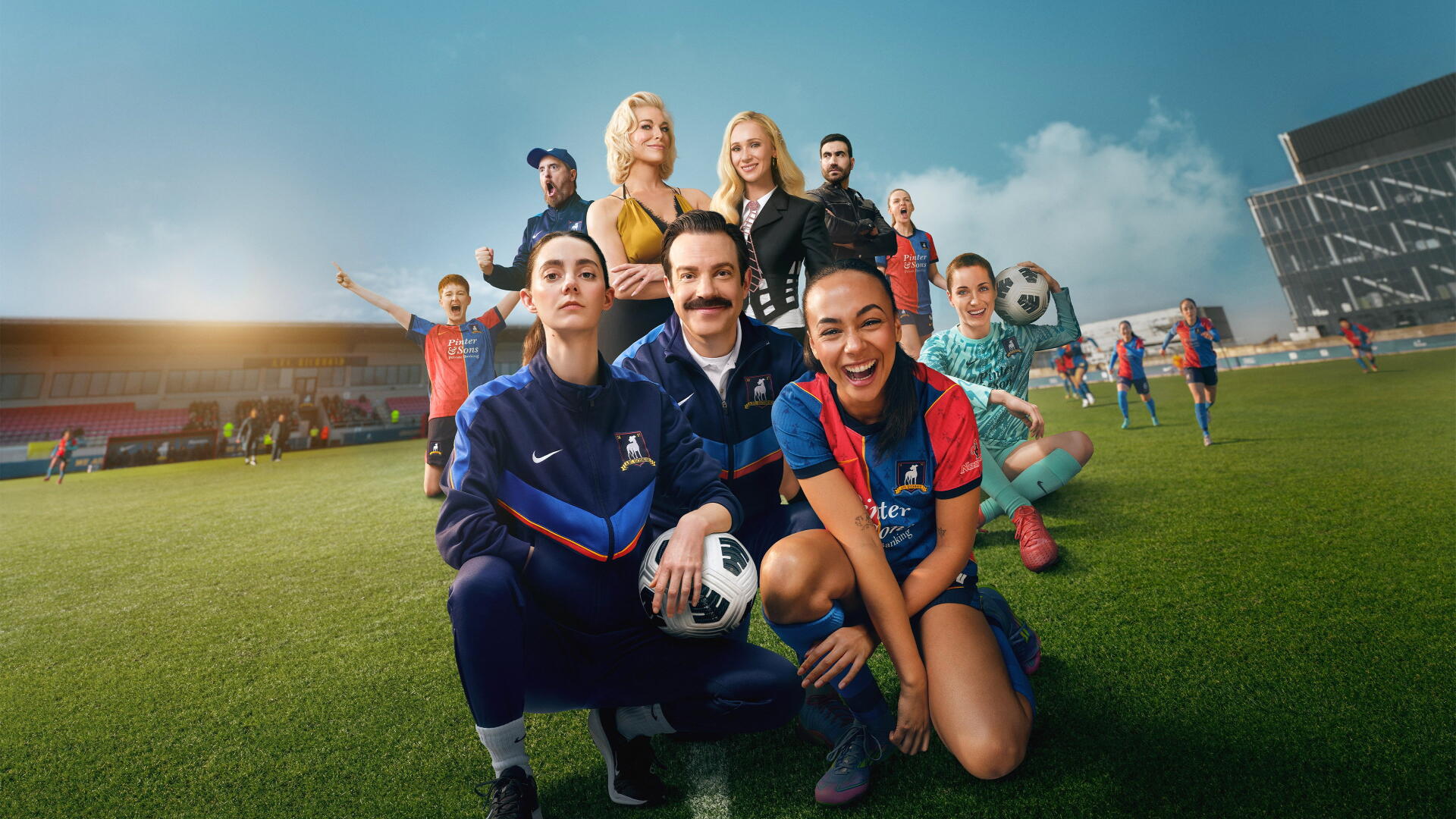 Ted Lasso cast posing on a sunlit soccer pitch, smiling and holding a ball — vibrant 4K Ultra HD PC desktop wallpaper and background.